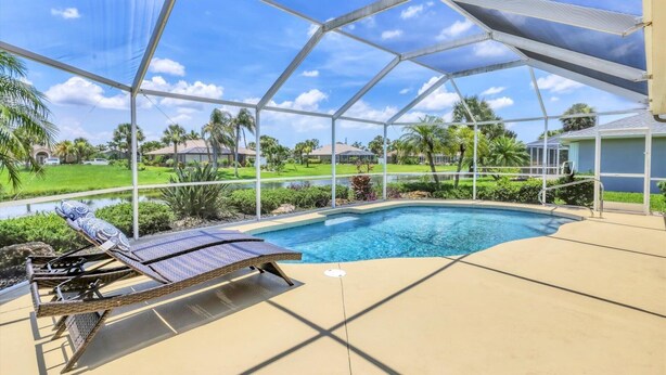 A covered outdoor swimming pool with a lounge chair and a view of a residential area. - Rotonda West Private Pool Vacation Home On Canal (Rotonda West)
