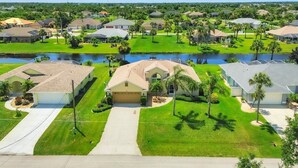 A residential area with houses, a water body, and well-maintained lawns. - Rotonda West Private Pool Vacation Home On Canal (Rotonda West)