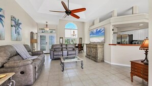 A spacious living room with a gray sofa, a leather recliner, a glass coffee table, and a ceiling fan. - Rotonda West Private Pool Vacation Home On Canal (Rotonda West)