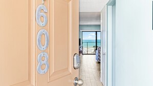 A hotel entrance with a numeric keypad door lock, a balcony with a view of the beach, and a tiled floor. - Direct Oceanfront Condo w/ Pool, Private Balcony & Ocean-View Master Bedroom (Cape Canaveral)