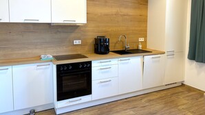 Una cocina moderna con armarios blancos, salpicadero de madera, estufa negra y un lavamanos.