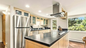 A modern kitchen with stainless steel appliances, wooden cabinets, and a large island. - Bigwood Basecamp with Mountain Views & Great Location (Ketchum)