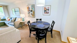 A modern living room with a round table, black chairs, a sofa, and a lamp.