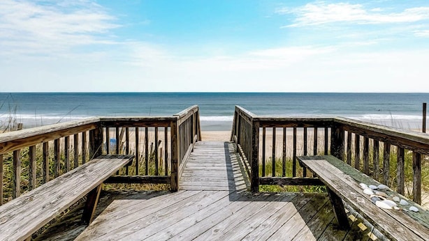 A wooden boardwalk leading to a beach with a clear view of the ocean. - Breakers | Oceanfront (Nags Head)