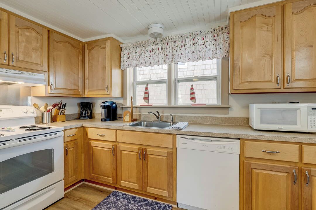 A kitchen with wooden cabinets, a white stove, a dishwasher, and a microwave.