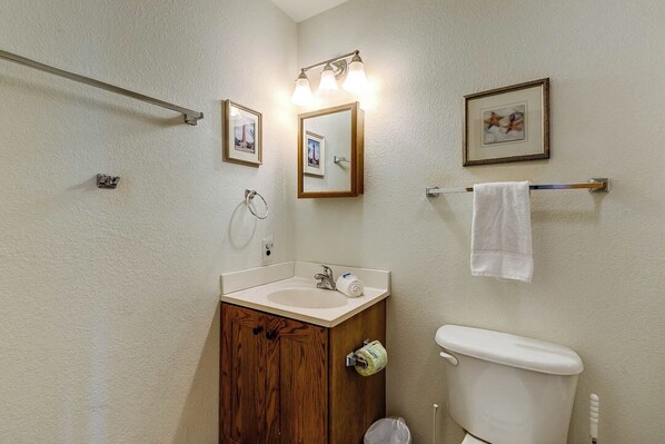 A bathroom with a wooden vanity, a sink, a toilet, and framed pictures on the wall.