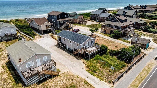 A coastal residential area with houses, a beach, and a road.