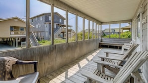 A covered outdoor area with wooden benches and a view of neighboring houses.