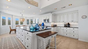 A spacious kitchen with white cabinetry, a large island, and a herringbone floor pattern. - Tide Together | 880 ft to the beach (Corolla)