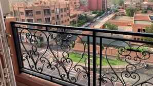 A balcony with wrought iron railings overlooking a cityscape with buildings and a mountain in the background. - Comfortable apartment in the center of Gueliz, close to all amenities. (Marrakech)