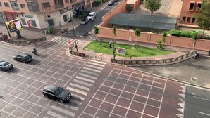 A multi-level parking structure with a central landscaped area, surrounded by buildings with balconies and signage. - Comfortable apartment in the center of Gueliz, close to all amenities. (Marrakech)