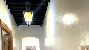 A hallway with a wooden door, a patterned rug, a marble floor, a wall-mounted phone, and a ceiling light fixture. - Comfortable apartment in the center of Gueliz, close to all amenities. (Marrakech)