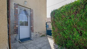 A building with a door, a small step leading to the entrance, and a hedge beside it. - La Maison d'à côté - CRANCEY (CRANCEY)
