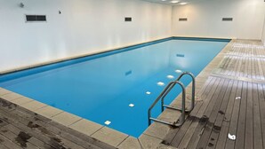 Ein Innenpool mit Holzboden, Metallleiter und Fliesenboden.