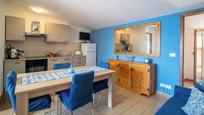 Une cuisine compacte avec un coin repas, un meuble en bois et un grand miroir.