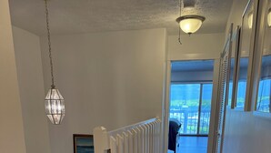 A hallway with a white railing, a patterned carpet, and a view of a balcony. - Charming 3-bedroom townhome with a river view and a 40 boat slip in Fort Pierce (Fort Pierce)