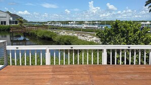 A wooden deck with a white railing overlooking a marina with boats and a clear blue sky. - Charming 3-bedroom townhome with a river view and a 40 boat slip in Fort Pierce (Fort Pierce)