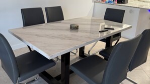 A modern dining area with a marble table, black chairs, and a kitchen in the background. - Charming 3-bedroom townhome with a river view and a 40 boat slip in Fort Pierce (Fort Pierce)
