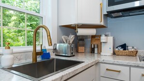 A modern kitchen with a sink, stainless steel appliances, and a window with a view of greenery. - Walk to Beach & Pier | 1BR Suite with Pool & Kitchenette (Old Orchard Beach)