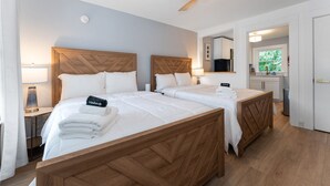 A hotel room with two beds, a ceiling fan, a bathroom with a sink, and a view of greenery outside. - Heated Saltwater Pool  Short Walk to Beach Pier 9 (Old Orchard Beach)