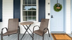 A porch with two chairs and a small table, a blue door with a welcome sign, and a window with shutters. - Heated Saltwater Pool  Short Walk to Beach Pier 9 (Old Orchard Beach)