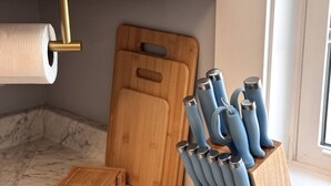 Eine Küche mit Marmorarbeitsplatte, einem Holzschneidebrett, einer Küchenpapierrolle und einem Messerblock mit blauen Knäufen.