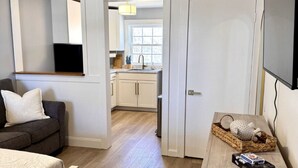 A compact living space with a kitchenette, a sofa, a dining table, and a ceiling fan.