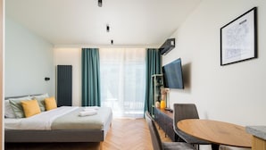Une chambre d’hôtel moderne équipée d’un lit, d’une table à manger, d’un téléviseur et d’une carte affichée au mur.