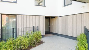 Un bâtiment moderne doté d’une cour intérieure, comprenant un sentier, un lambris en bois et de petites plantes vertes.