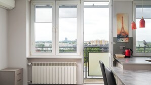 A modern kitchen with a view of the city, a radiator, and a dining area with a chair.