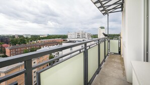 A balcony with a view of surrounding buildings and a cloudy sky.
