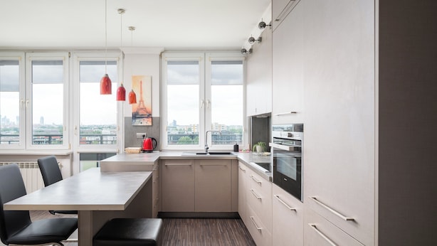 A modern kitchen with a large island, white cabinets, and a view of the city.