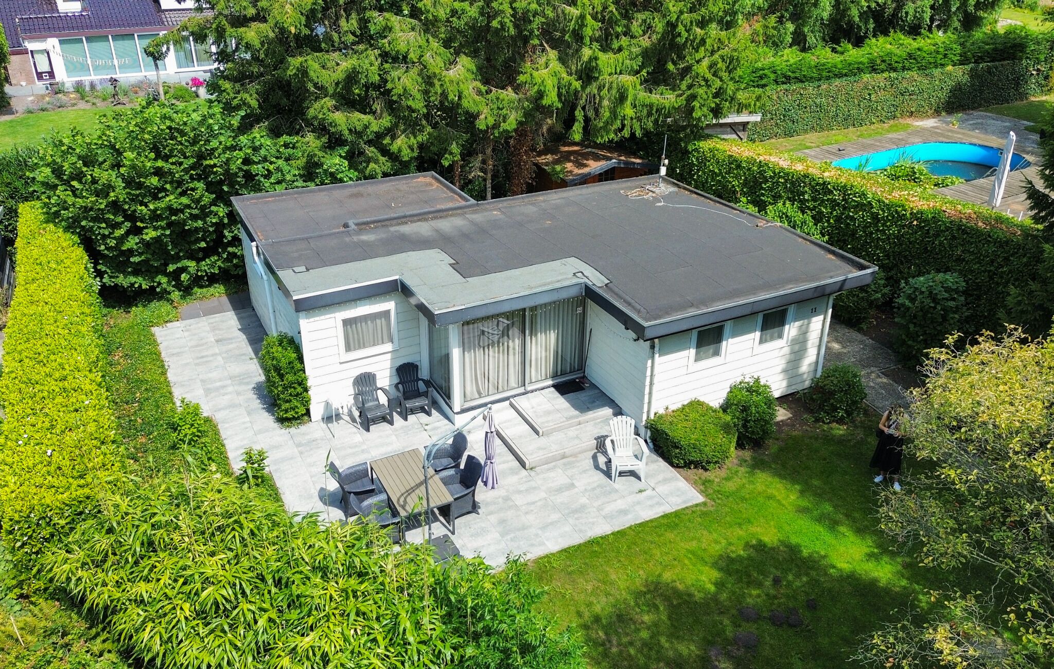 Ein zweistöckiges Haus mit einer Terrasse, einem Swimmingpool und einem gepflegten Garten.