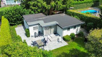 Ein zweistöckiges Haus mit einer Terrasse, einem Swimmingpool und einem gepflegten Garten.