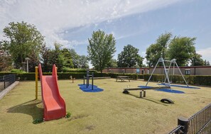 A playground with a red slide, swings, and a blue play area.