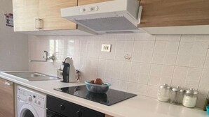 A kitchen with wooden cabinets, a built-in oven, a washing machine, and a sink.