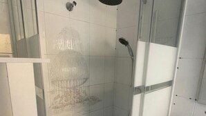 A modern bathroom with a glass shower enclosure, a white tiled wall, and a glass door.