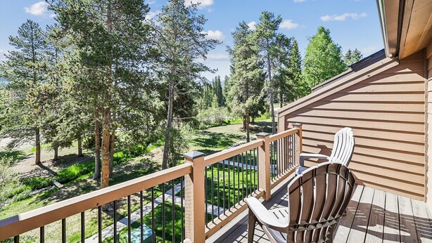 A wooden deck with a railing, a chair, and a view of a forested area. - Cedars 3: Ski-In/Out Peak 9 Townhome, Fireplace, Pool & Hot Tub Access. (Breckenridge)