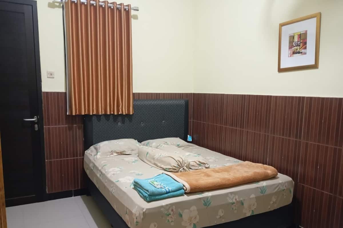 Un dormitorio con cama, cortinas, un cuadro enmarco y suelo de baldosas.