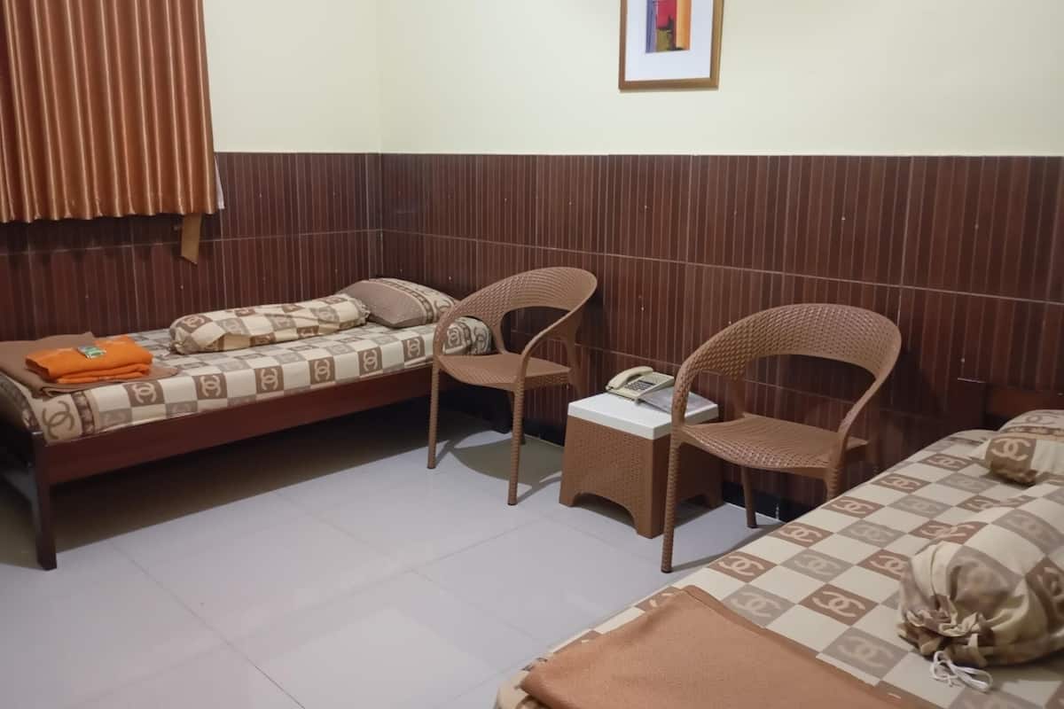 Una habitación con dos camas, una silla y una mesita.