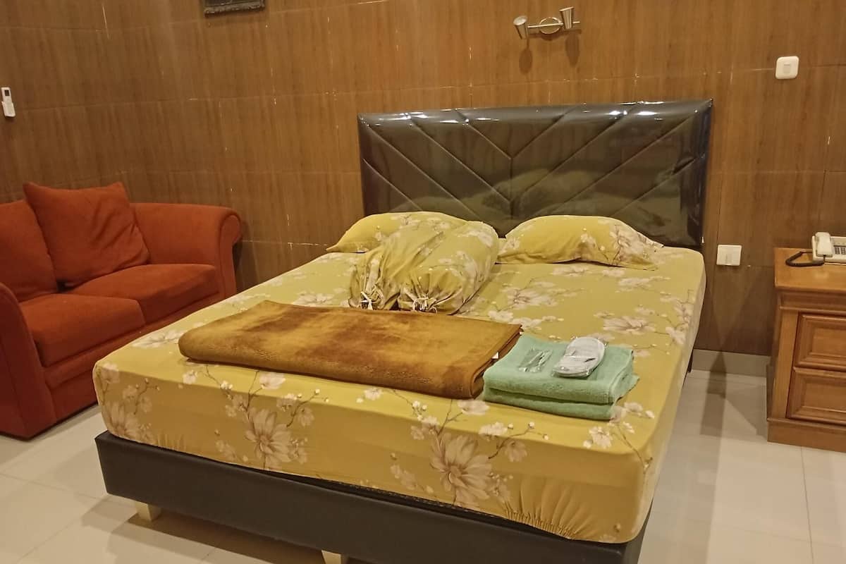Una cama bien tendida con ropa de cama floral, un plaid marrón y una toalla verde.