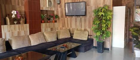 A modern living room with a sectional sofa, a glass coffee table, and a large potted plant.