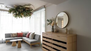A modern living room with a sectional sofa, a round coffee table, and a wooden cabinet with drawers. - hotel hisoca ikebukuro (Tokyo)