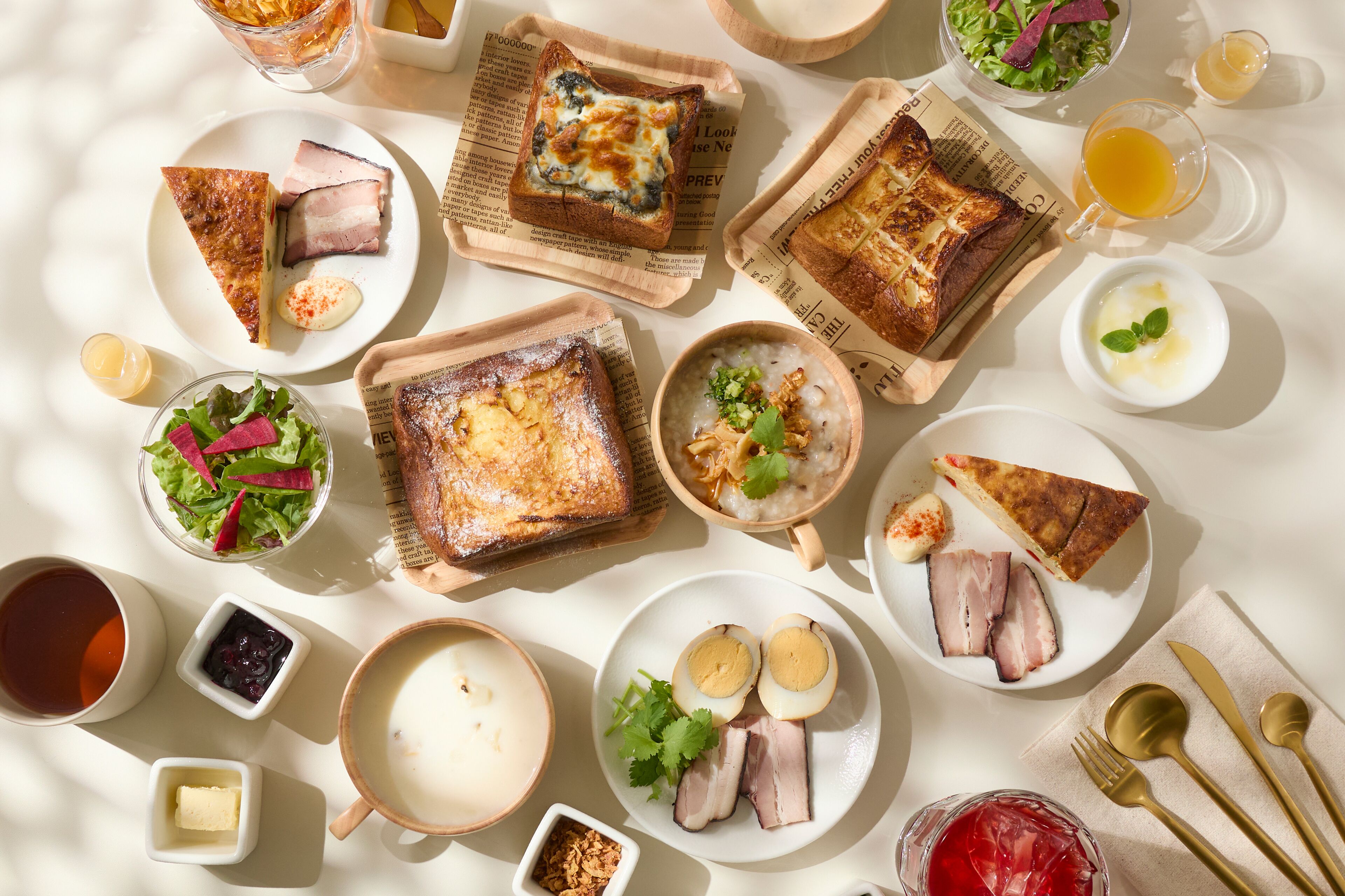 A table with various food items and drinks, including toast, eggs, and a bowl of soup.