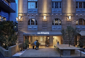 A hotel entrance with a modern facade, a wooden deck, and outdoor seating. - hotel hisoca ikebukuro (Tokyo)