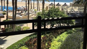 A beach view from a balcony with palm trees, lounge chairs, and a pool. - Chic 1-bedroom apartment with WiFi, AC in beautiful San Jose del Cabo (San Jose del Cabo)