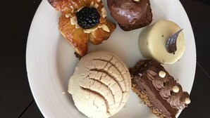 A plate with various pastries including a star-shaped pastry, a round chocolate-covered item, a white round pastry, and a chocolate dessert with white cream. - Chic 1-bedroom apartment with WiFi, AC in beautiful San Jose del Cabo (San Jose del Cabo)
