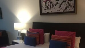 A neatly made bed with pink and blue bedding, a framed artwork above it, and a lamp on the nightstand. - Chic 1-bedroom apartment with WiFi, AC in beautiful San Jose del Cabo (San Jose del Cabo)