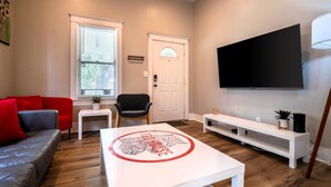 A living room with a sofa, a coffee table, a TV, a door, and a window.