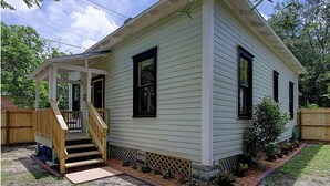 A single-story house with a covered porch, a front door, and a small staircase leading to the entrance.